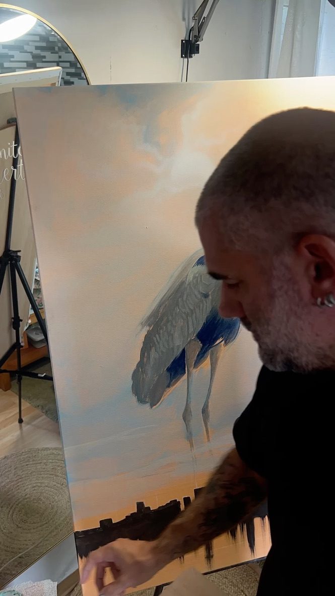 Miguel pintando una garza sobre lienzo en el estudio